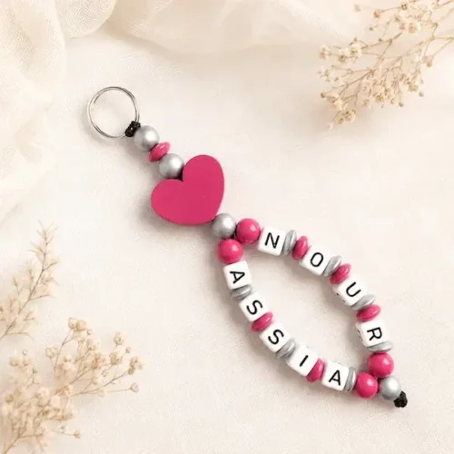 Porte-clés personnalisé avec les prénoms Nour et Assia, grand cœur fuchsia et perles argentées