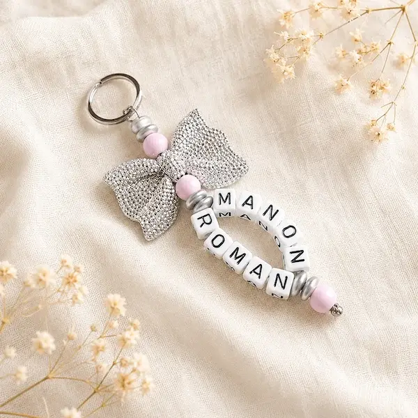 Porte-clés personnalisé avec les prénoms Manon et Roman, perles rose pâle et grand nœud argenté