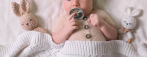 bébé avec sa tétine et ses doudous lapin