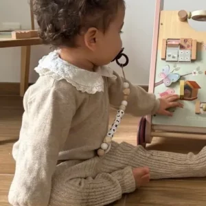 bébé avec une attache tétine personnalisée en bois et silicone conforme aux normes de sécurité